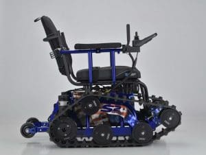 A motorized wheelchair with tank-like tracks instead of wheels, featuring an American flag design on the base and a joystick control on the armrest, shown against a plain light background.