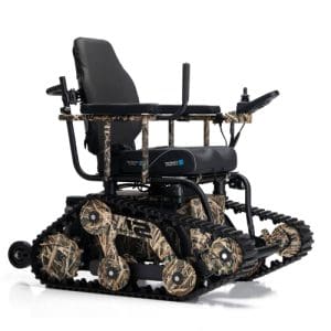 All-terrain wheelchair with rubber tank-like tracks, camouflage-patterned frame, cushioned black seat, armrests, and a joystick controller on the right side, designed for outdoor mobility over rough surfaces.
