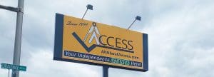 A yellow billboard for AllAboutAccess.com reads Since 1994 ACCESS. Your Independence, STARTS Here! with a logo of a person above the word ACCESS. A street sign below says “Calheshaw.”.