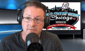A man wearing glasses and headphones speaks into a microphone in a studio. Behind him is a sign with a city skyline and the words Home Sweet Home Chicago, WGN Radio AM 720, Listen, Laugh & Learn, Saturdays 10am-1pm.