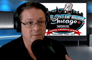 A man wearing glasses and headphones speaks into a microphone in a radio studio, with a screen behind him displaying Home Sweet Home Chicago and show details for WGN Radio 720.