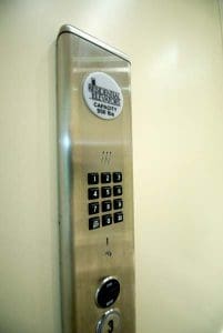 Close-up of a stainless steel residential elevator control panel with a numeric keypad, a circular switch labeled ON/OFF, and a sign indicating a 950 lbs capacity.