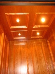 Wood-paneled ceiling and walls with four recessed lights illuminating the space, featuring decorative square molding details.