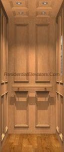 Wood-paneled residential elevator interior with recessed lighting in the ceiling and decorative trim on the walls and doors; hardwood floor visible at the bottom.