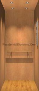 Wood-paneled residential elevator interior with recessed ceiling lights, a horizontal handrail along the back wall, a small shelf, and a control panel on the right wall.