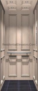 Interior of a modern residential elevator with light wood paneling, silver handrails on three sides, recessed ceiling lights, and a dark tiled floor.