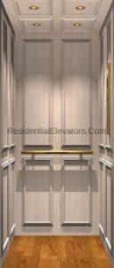 A residential elevator interior with light wood panel walls, recessed ceiling lights, a wooden floor, and a metal handrail along the back wall.