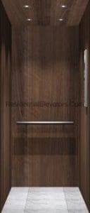A small, modern elevator interior with dark wood-paneled walls, a metal handrail, and a light gray marble floor. Recessed ceiling lights illuminate the compact space.