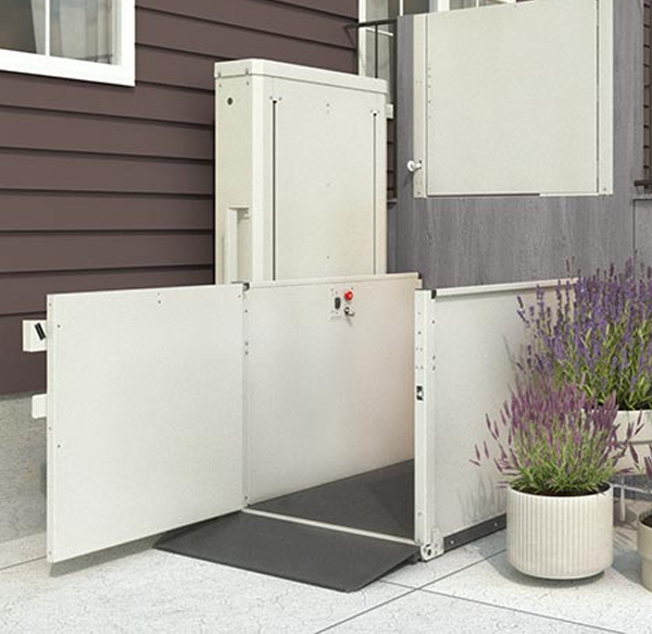 Vertical platform lift installed next to a porch, featuring a non-slip platform and safety gate by Access Elevator, Inc.