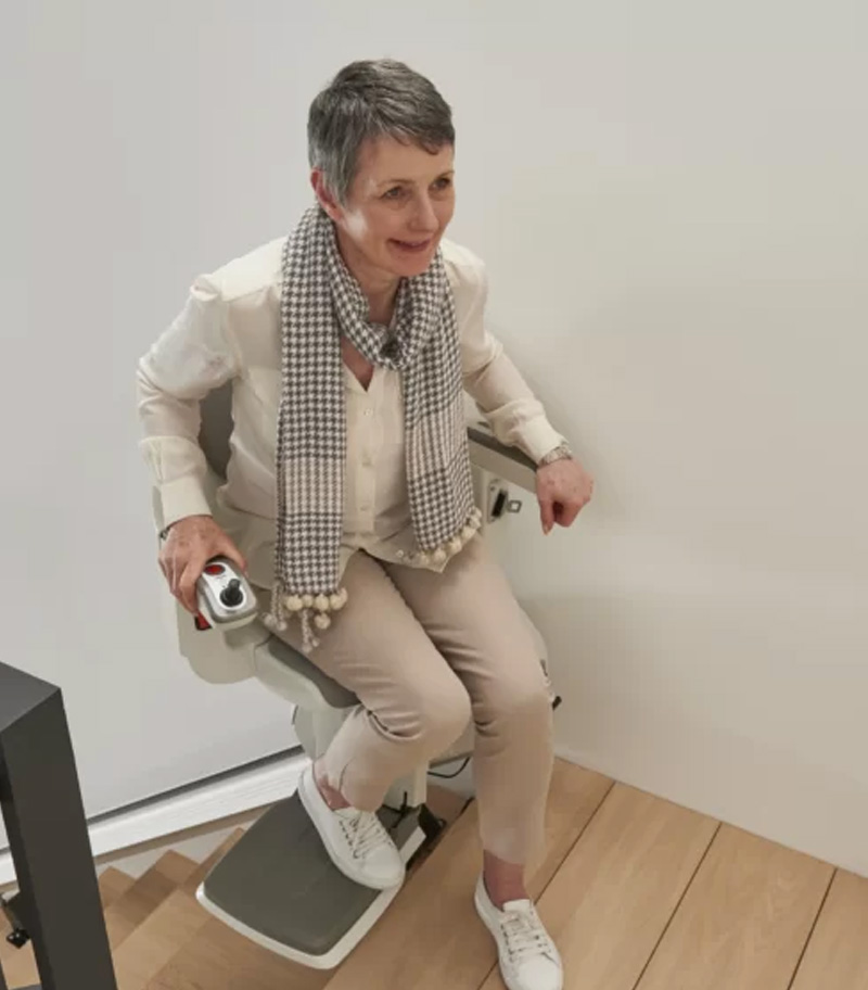 Access BDD HomeGlide Extra Straight Stair Lift Swiveled Out at Top of Stairs With User Making Safe and Easy Transfer