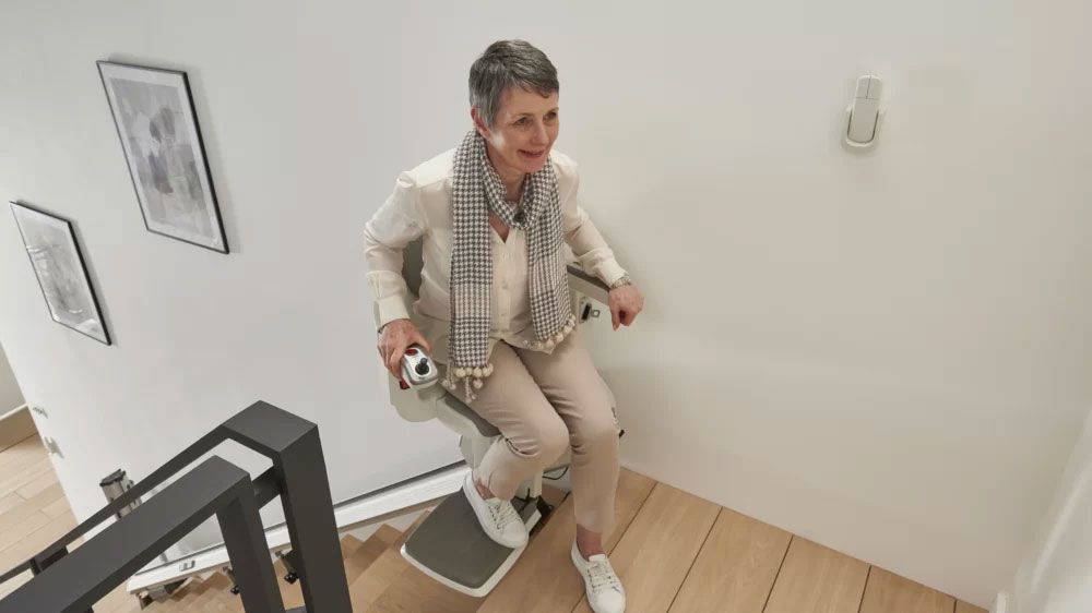 Access BDD HomeGlide Extra Straight Stair Lift Swiveled Out at Top of Stairs With User Making Safe and Easy Transfer