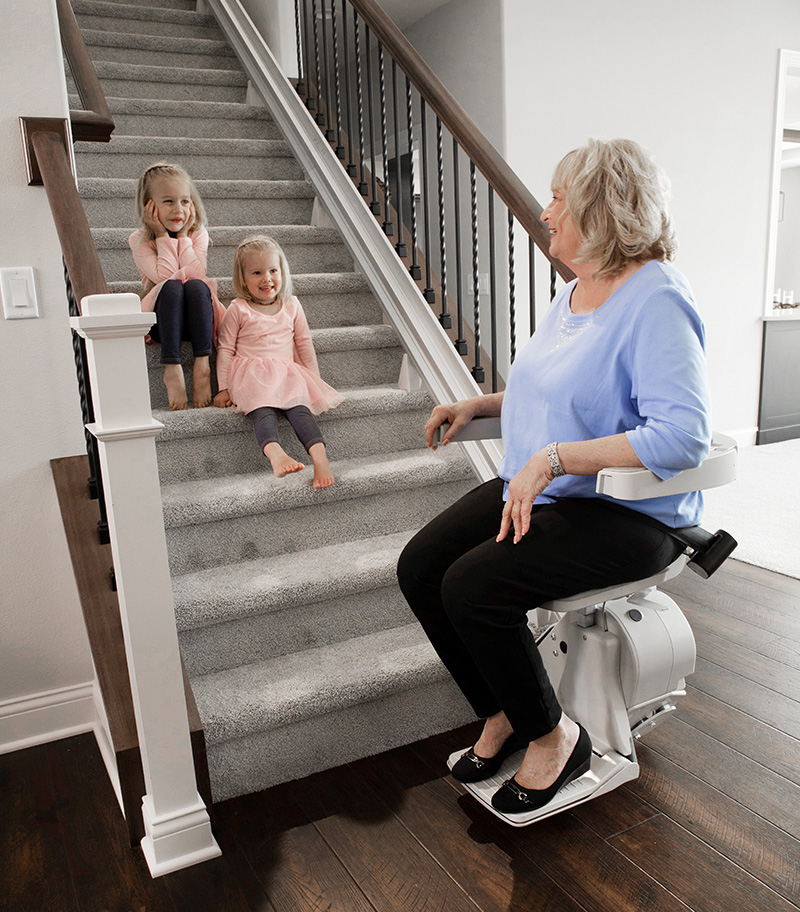 Bruno Elon Straight Stairlift with Grandma on Lift and Two Granddaughters on Home Stairs