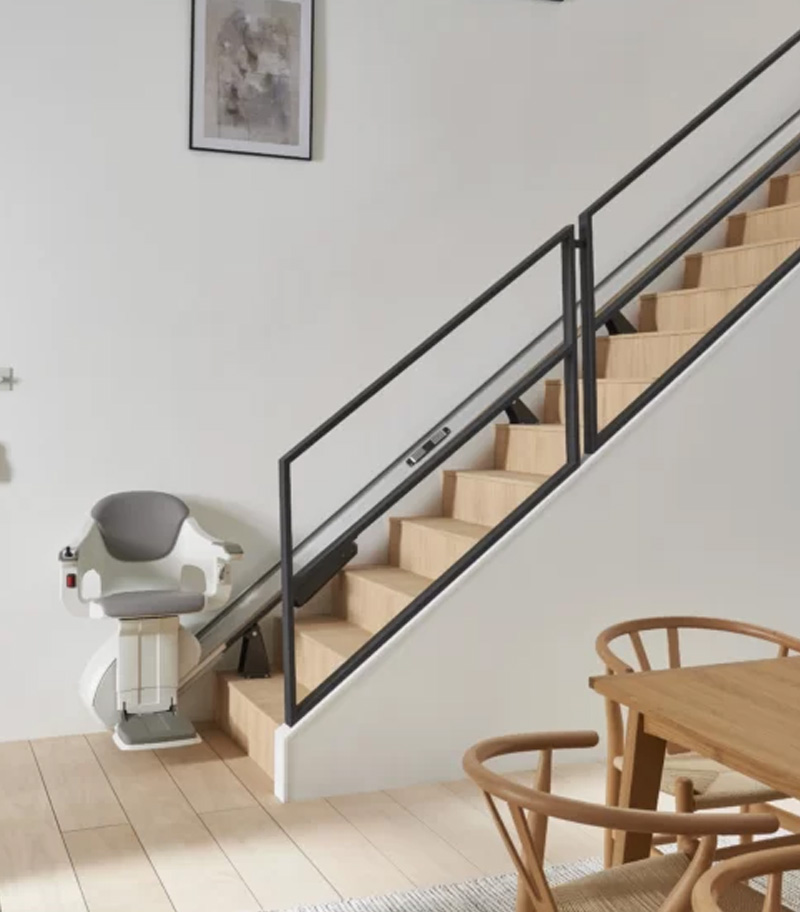 Access BDD HomeGlide Straight Stairlift with Lift in Riding Position on Home Staircase with Table in Foreground
