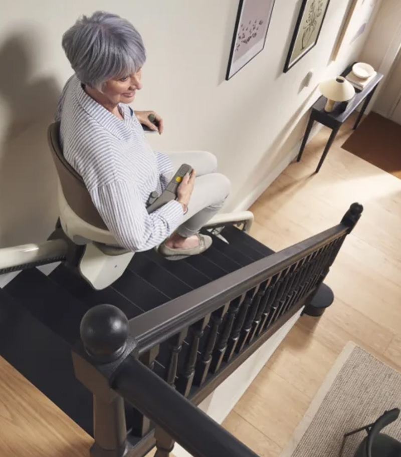 Rider Demonstrating Ease of Passage through Narrow Spaces or Doorways on Stairs With Access BDD HomeGlide Straight Stair Lift