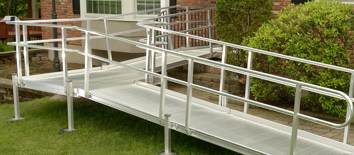 Aluminum modular residential wheelchair ramp from National Ramps with solid decking. Ramp turns to avoid running through bush