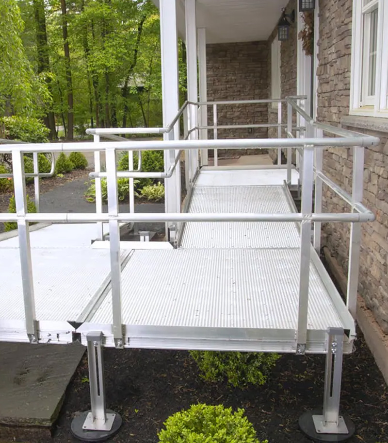 Residential aluminum wheelchair ramp with mesh decking for rain and snow and custom layout to fit owner's house.