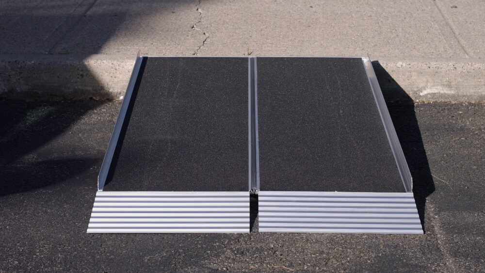 Bi-fold aluminum portable wheelchair ramp from National Ramps, allowing easy wheelchair access from street to curb