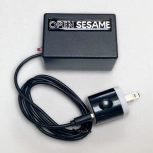 A black Automatic Door Opener by Open Sesame, featuring a connected black power cord and plug, displayed on a white background.