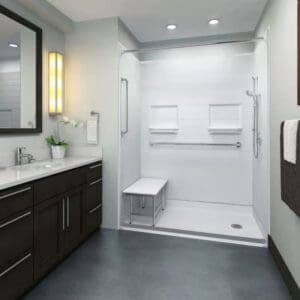 Modern accessible bathroom with a Roll-In Shower by Best Bath, foldable bench, grab bars, handheld showerhead, dark wood vanity, large mirror, white countertop with a potted plant, and towels neatly placed on a rack.