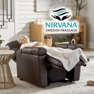 An elderly woman relaxes in a Cloud+ Large - Lift Chair by Golden Technologies, eyes closed and covered with a knit blanket. The bright, cozy room enhances her comfort. "NIRVANA SWEDISH MASSAGE" with its logo appears above her.
