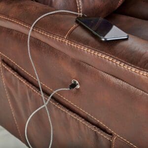 A smartphone charges via a cable plugged into the USB port on the side of the Dione Large - Lift Chair by Golden Technologies, with a pocket visible below.
