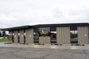 A single-story tan building with large windows and signs reading Access Mobility Center on the exterior, situated in a parking lot on a cloudy day.
