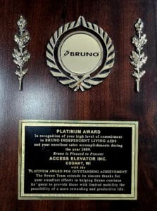 A wooden plaque with gold accents and a central Bruno logo, featuring a gold plate that recognizes Access Elevator Inc. for outstanding sales achievements with Bruno Independent Living Aids in 2009.
