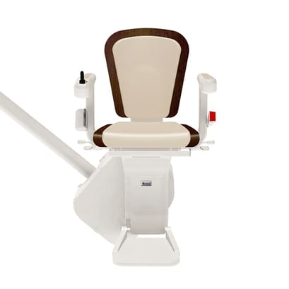 The Freecurve Curved Stair Lift by Handicare features a beige and brown chair with armrests, a left-arm joystick control, and a red button on the right, all mounted on a rail for easy residential stairway access.