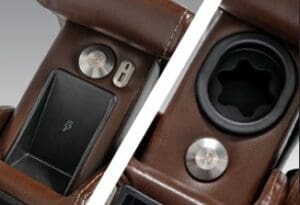 Close-up of the VivaLift Premier PLR-5900 lift chair's brown leather armrest, featuring a wireless charging pad, two metallic buttons, a USB port, and a cup holder with flexible insert by Pride Mobility.
