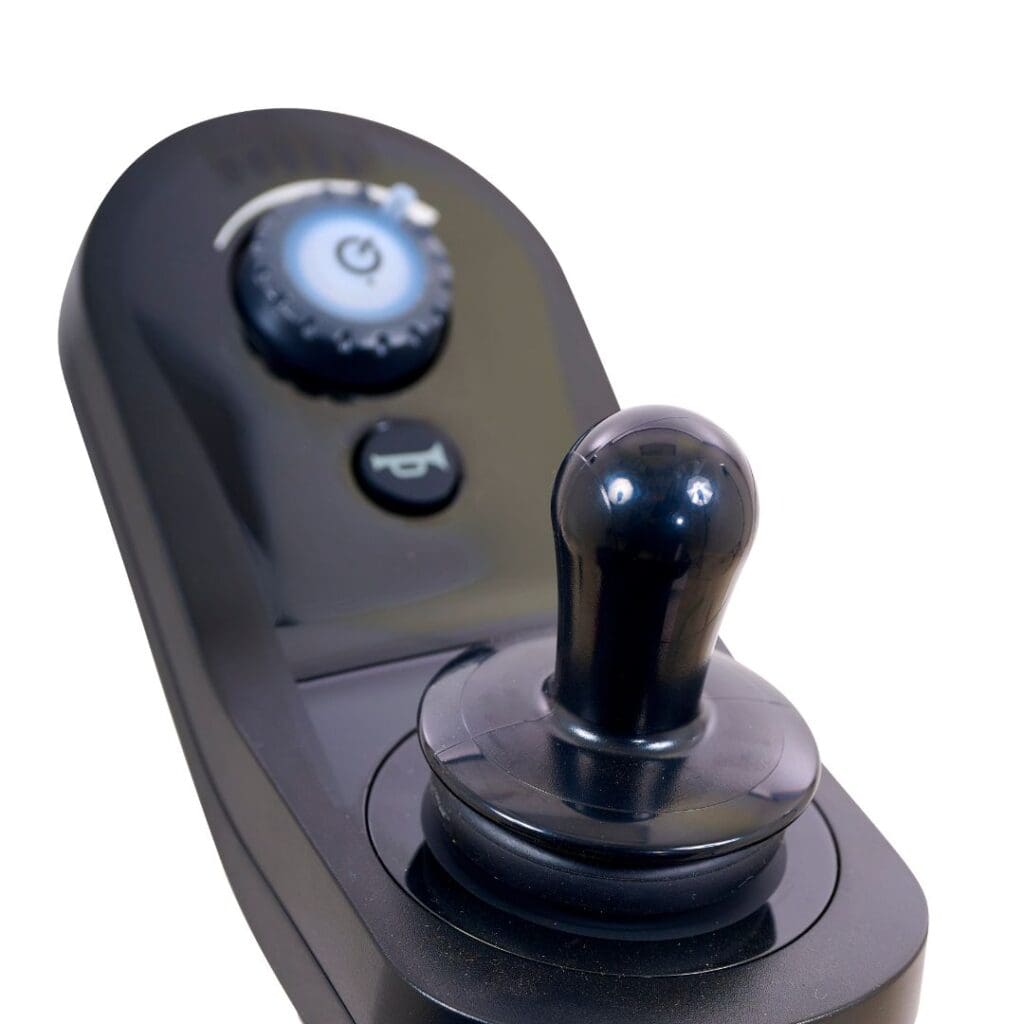 Close-up of a black joystick controller with round knob, circular power button, and speed dial for operating the BuzzAbout - Power Wheelchair by Golden, shown against a white background.