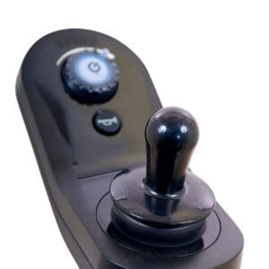 Close-up of a black joystick controller with round knob, circular power button, and speed dial for operating the BuzzAbout - Power Wheelchair by Golden, shown against a white background.