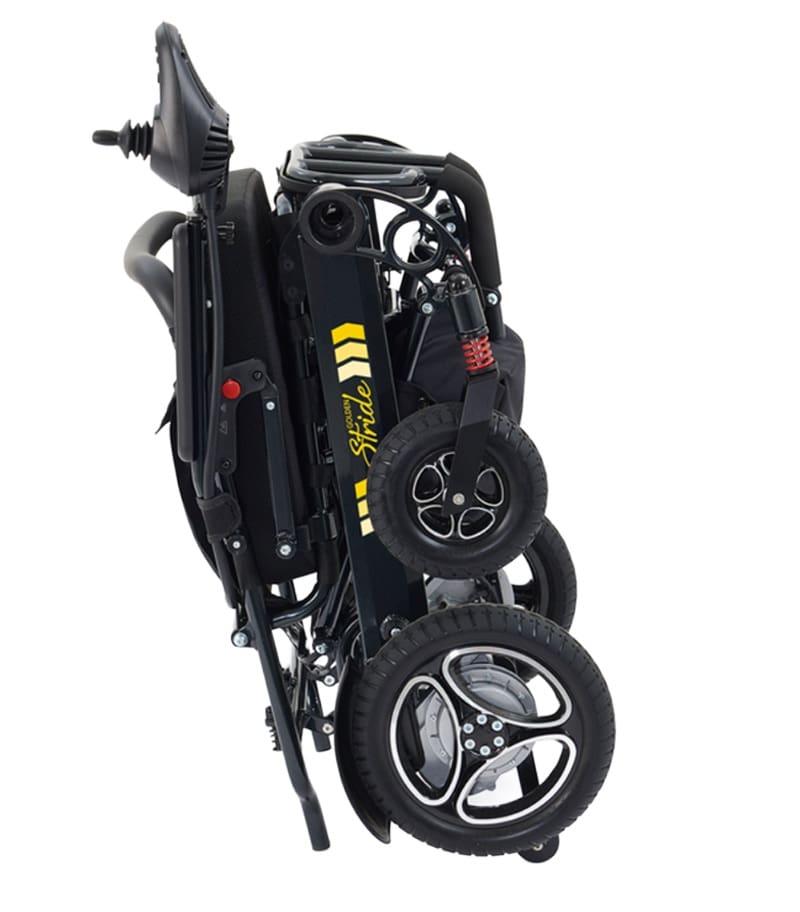 The Stride - Power Wheelchair by Golden is displayed in its fully collapsed, upright position, with its black frame, closely stacked wheels, and a visible yellow logo on the frame. The Stride - Power Wheelchair by Golden is displayed in its fully collapsed, upright position, with its black frame, closely stacked wheels, and a visible yellow logo on the frame.