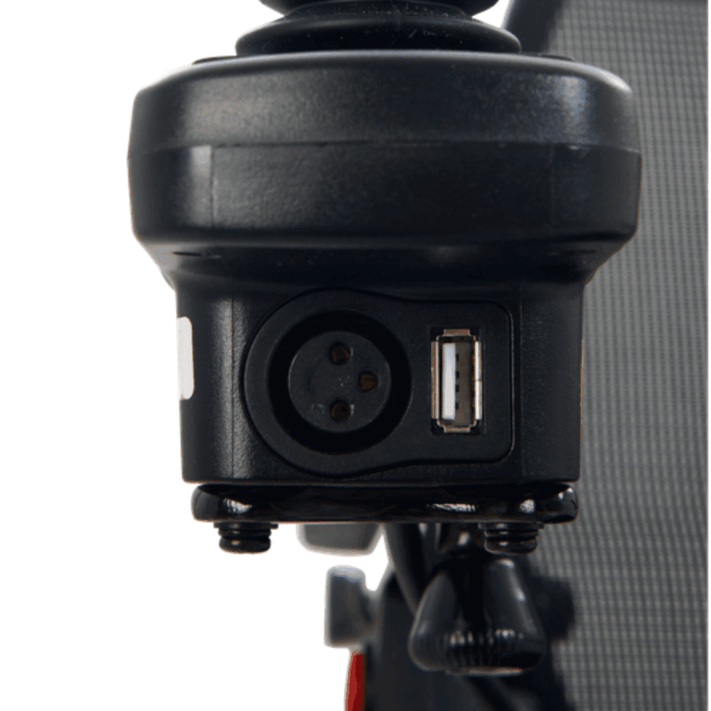 Close-up of a black electronic component on the Cricket - Power Wheelchair by Golden, featuring a three-pin circular connector and USB port, secured with screws to a vertical surface.