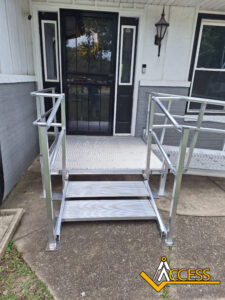A silver metal wheelchair ramp with handrails is installed in front of a porch, providing access to a door. The ACCESS logo is in the bottom right corner of the image.
