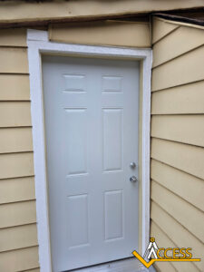 A white exterior door with two locks is set in cream-colored siding. The Access logo is visible in the bottom right corner of the image.