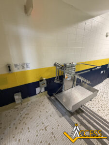 A wheelchair lift is installed beside a staircase with yellow and navy stripes on the wall. The floor is tiled in white and tan. The word ACCESS with an accessibility icon is overlaid on the image.