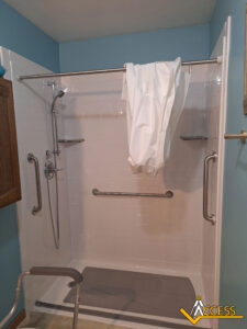 A walk-in shower with grab bars on three sides, a handheld showerhead, a shower chair, and a white shower curtain draped over the rod. ACCESS logo appears in the bottom right corner.