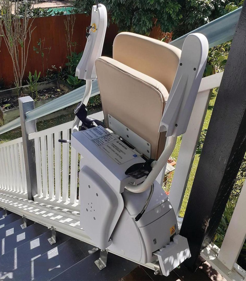K2 stairlift with L seat installed by Savaria Australia Savaria K2 outdoor stairlift with the seat, armrests, and footrest folded up, showcasing its compact, space-saving design. The weather-resistant stairlift is mounted on an exterior staircase and features a durable rail system designed to provide reliable outdoor accessibility while keeping the stairs clear when not in use.
