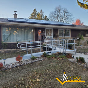 A single-story house with a metal wheelchair ramp leading to the front door. The yard has small plants and autumn leaves, and there is a logo in the bottom right corner that says ACCESS.