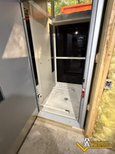 An unfinished residential elevator shaft with a partially installed elevator cab, exposed insulation on the right, and the Access Lifts logo at the bottom right corner.