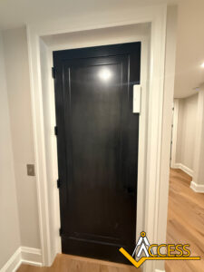 A closed dark wooden door with white trim is set in a light-colored hallway with wooden flooring. The Access logo appears in the lower right corner of the image.