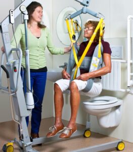 Caregiver helping patient over a toilet in a sling using a mobile patient lift 1641 by SureHands