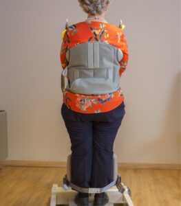 Rear view of a patient using the SureHands Stand Assist 2620 with a supportive standing sling secured around the torso, demonstrating proper positioning for safe sit-to-stand transfers and assisted mobility.