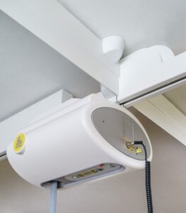 SureHands Traverse Rail ceiling lift motor with a traverse rail connector mounted on an overhead parallel track system for smooth full-room patient transfers.