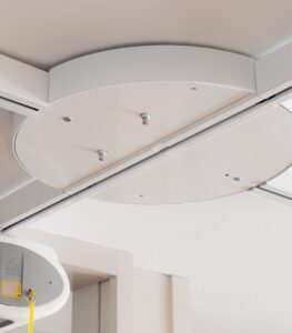 SureHands ceiling lift turntable mounted on an overhead track, allowing smooth 4-way track transitions for accessing multiple transfer locations in a home or healthcare setting.