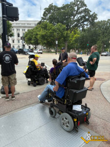 Carl Schulze leads advocates through the final stretch of the journey while participants carry signs supporting disability rights, independent living, and essential home-care services.