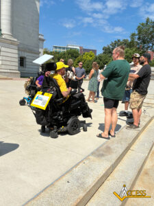 Carl Schulze travels toward the State Capitol in his wheelchair, surrounded by Access representatives and disability rights activists during the final mile of his 11-day journey.
