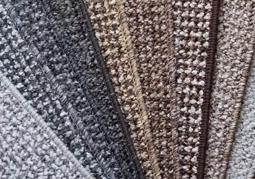 A semi-circle display of Accessible Flooring carpet samples in neutral shades from light grey to dark brown, each with textured, looped pile suited for residential accessible flooring solutions.